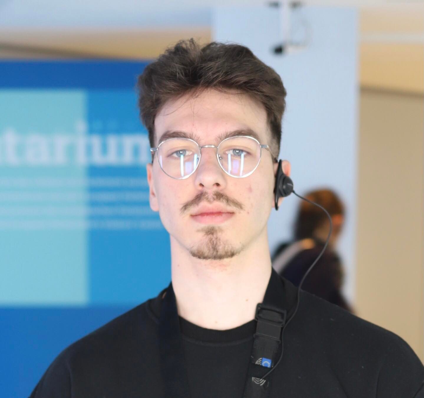 Web developer with a microphone, black t-shirt with a white and blue background